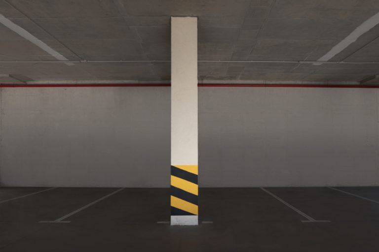 Empty car parking garage with warning stripes on column